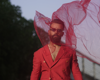 man in red suit posing with red fabric blowing in his face