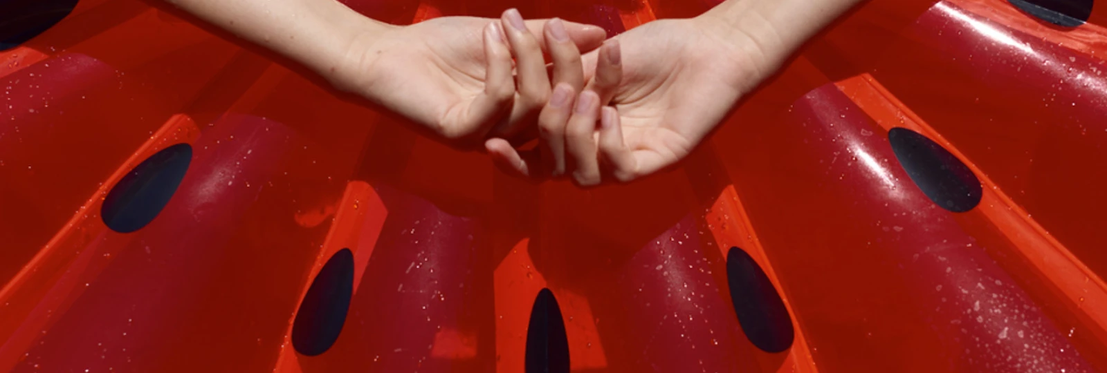 woman laying on inflatable red watermelon with hands above head