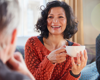 woman in red jumper holding mug smiling at friend