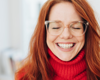 Woman with red jumper and hair smiling