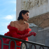 woman in extravagant red dress looking over balcony