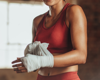 woman in red ret smiling and wrapping bandages for boxing