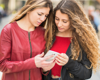 Two women in red outfits checking a phone together