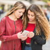 Two women in red outfits checking a phone together