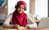 woman in red headscarf smiling with headphones studying