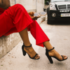 cropped image of woman's red pants and black heels holding sunglasses