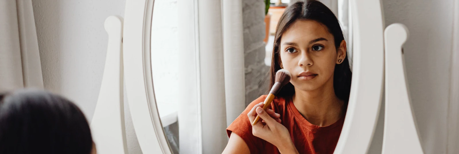 young girl looking into vanity mirror doing her makeup