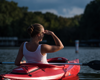woman in white tank top sitting in red kayak on lake