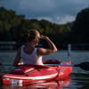woman in white tank top sitting in red kayak on lake
