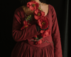 close shot of woman holding red flowers in a red dress