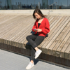 woman sat outside wearing red jumper on her phone