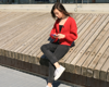 woman sat outside wearing red jumper on her phone