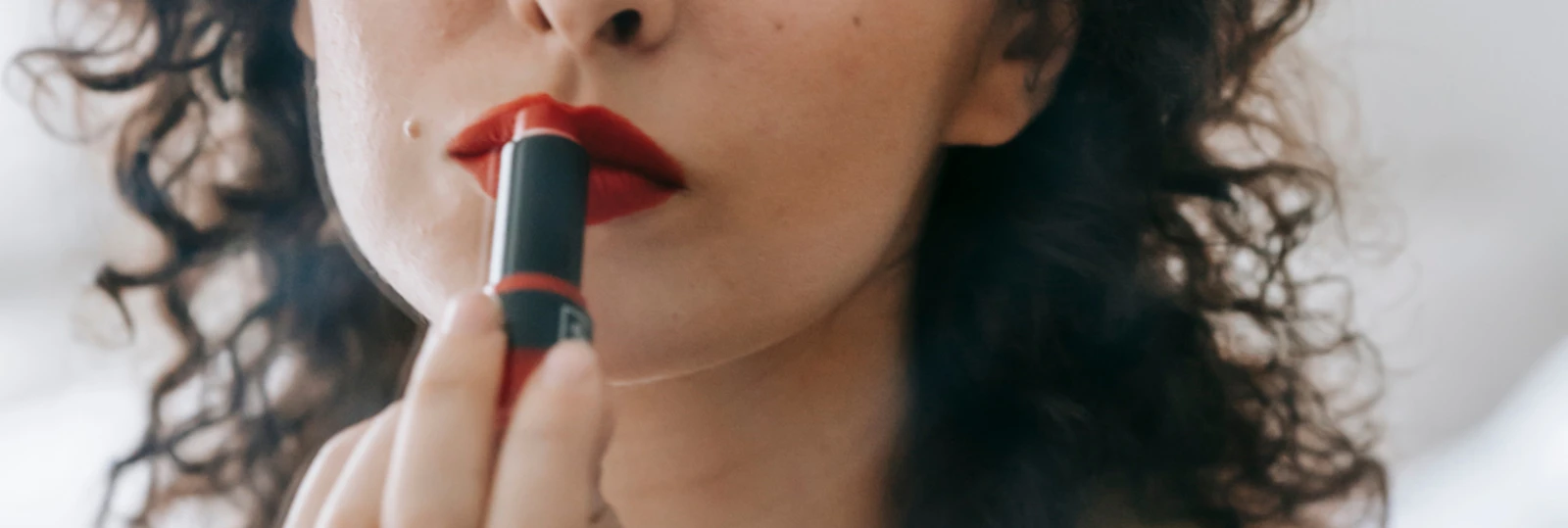 woman applying red lipstick in a mirror