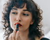 woman applying red lipstick in a mirror