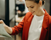 woman wearing a red blazer looking at a clipboard of paper