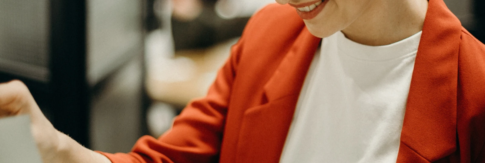 woman wearing a red blazer looking at a clipboard of paper