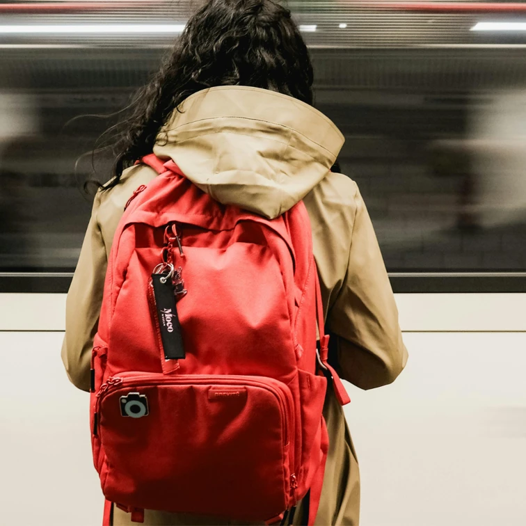 woman with back turned away wearing red backpack