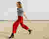 happy woman running wearing red trousers