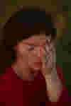 woman looking down covering one eye looking sad