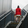 woman in red blazer walking up stairs away from camera