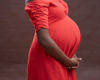 pregnant woman holding stomach in red dress