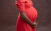 pregnant woman holding stomach in red dress
