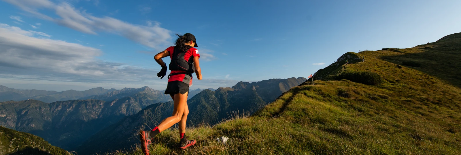Woman in red running gear on grassy mountain