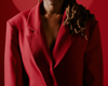 zoomed in image of woman wearing a red blazer in front of a red backdrop