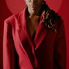 zoomed in image of woman wearing a red blazer in front of a red backdrop