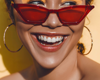 woman smiling wearing red sunglasses with bright orange eye-shadow